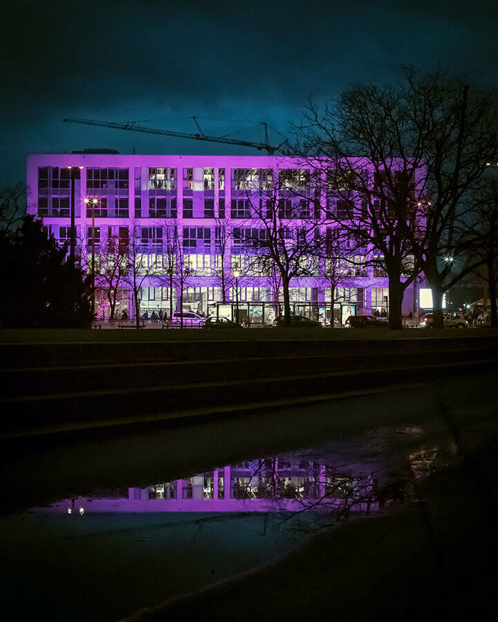 Potsdamer Bildungsforum spiegelt sich bei Nacht in einer Pfütze