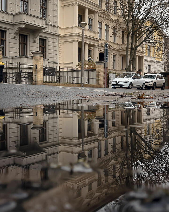 Häuser spiegeln sich in der Pfütze.